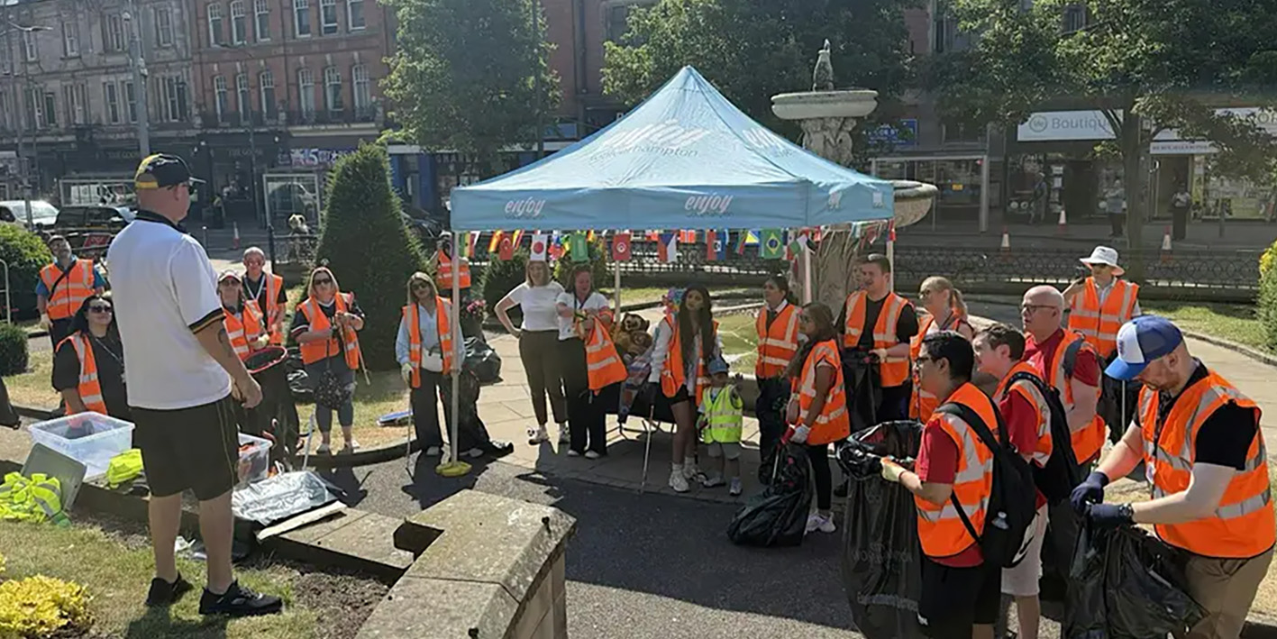 Photograph of volunteer litter pickers  in high-vis jackets garthered in Wolverhampton city centre with Enjoy Wolverhampton gazebo in background