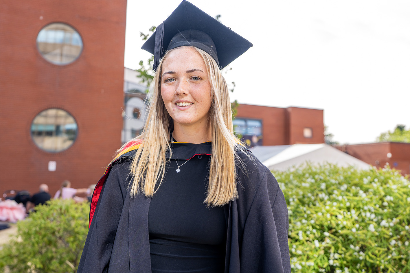 Madi Highfield wearing graduation cap and gown in the courtyard