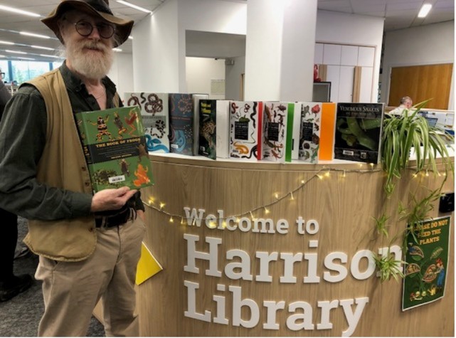 Person standing in front of a library desk with books