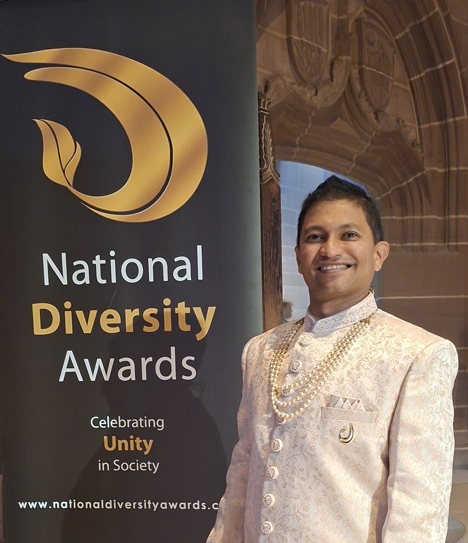 Pliny Soocoormanee - male standing in from of a banner
