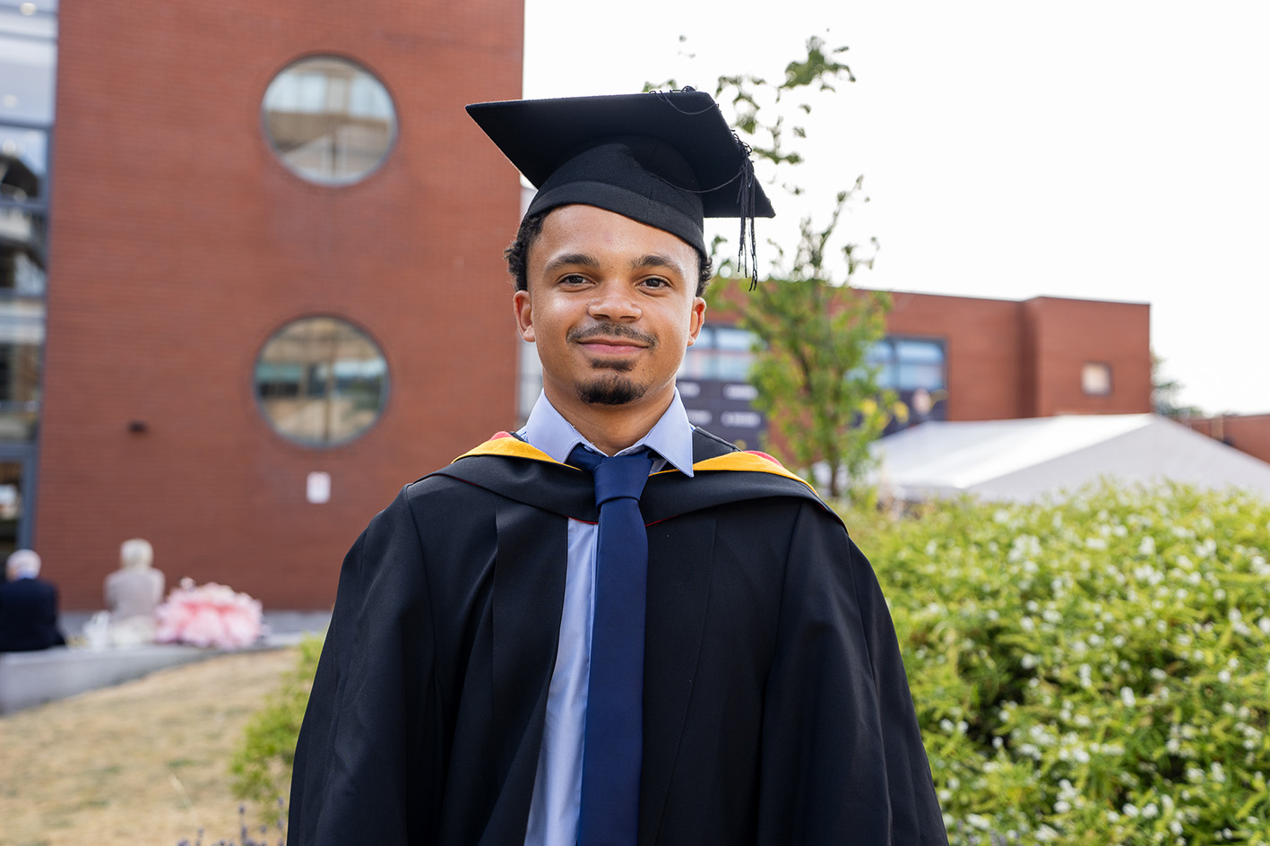 Shaun Johnson wearing graduation cap and gown in the courtyard
