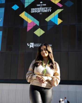 Angel Morphew standing in front of a building with the University of Opportunity branding on its side