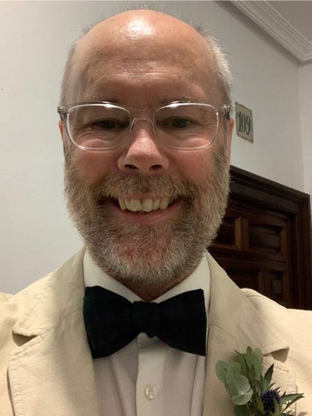 Headshot of David Matheson wearing a white suit jacket with a black bowtie