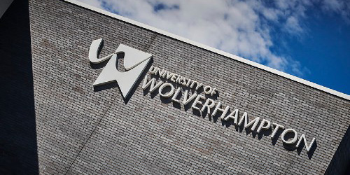 Photo of the WLV logo at the top of the Business School building, with blue, cloudy sky in background