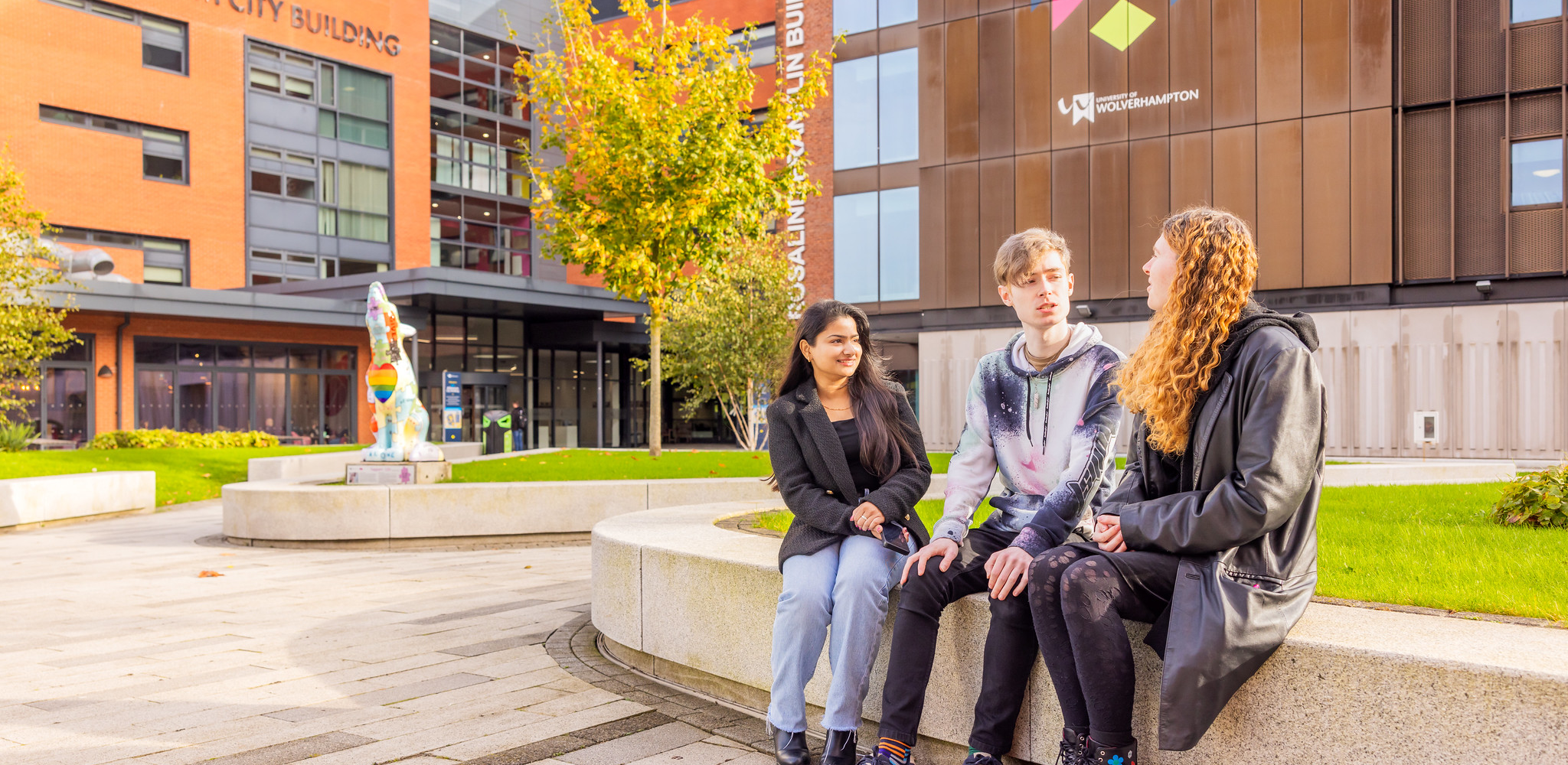 three students sitting in the City Campus Courtyard