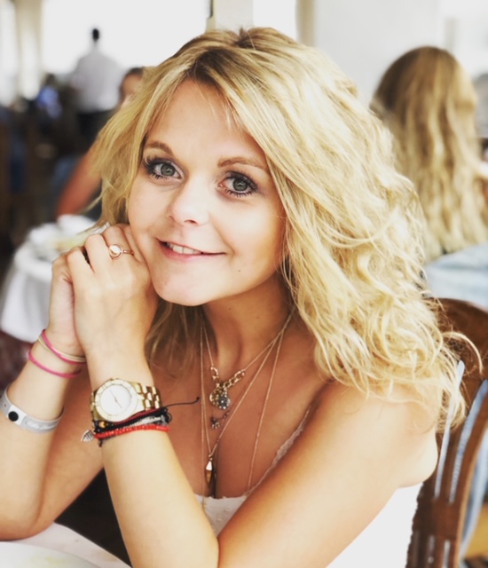 Charlotte Dunn sitting at a table, facing the camera and smiling