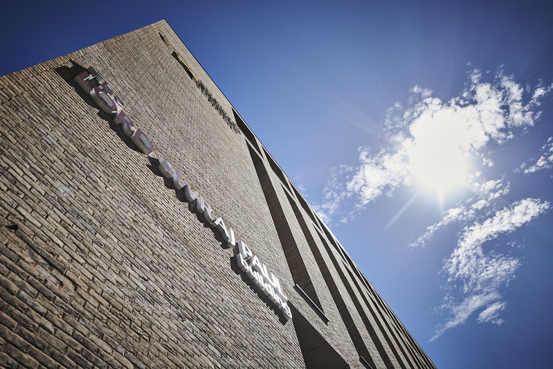 Photo taken of the business campus looking upwards towards the sky, there's a cloud floating high above
