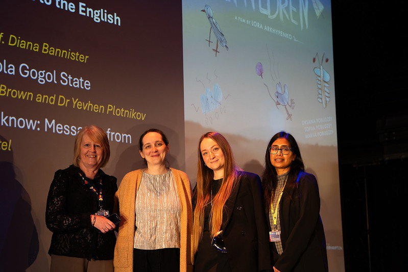 University representatives and filmmaker  Lora Arkhypenk on stage with a backdrop saying 'children' in the background