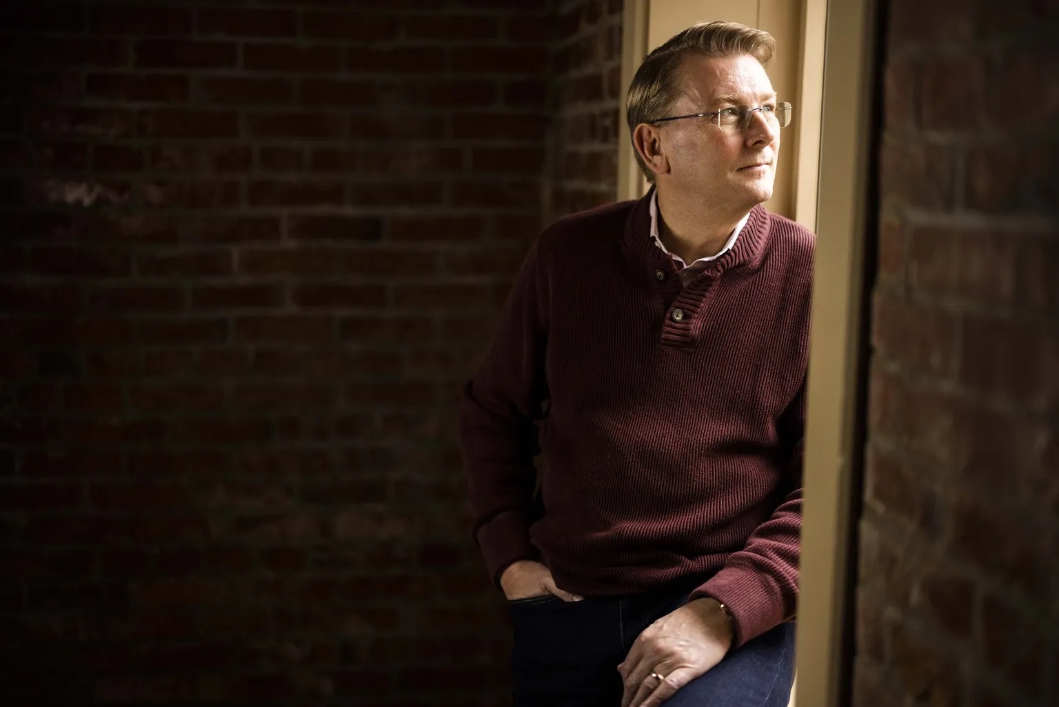 Kaj Pederson sits on a windowsill and looks from the window into the distance