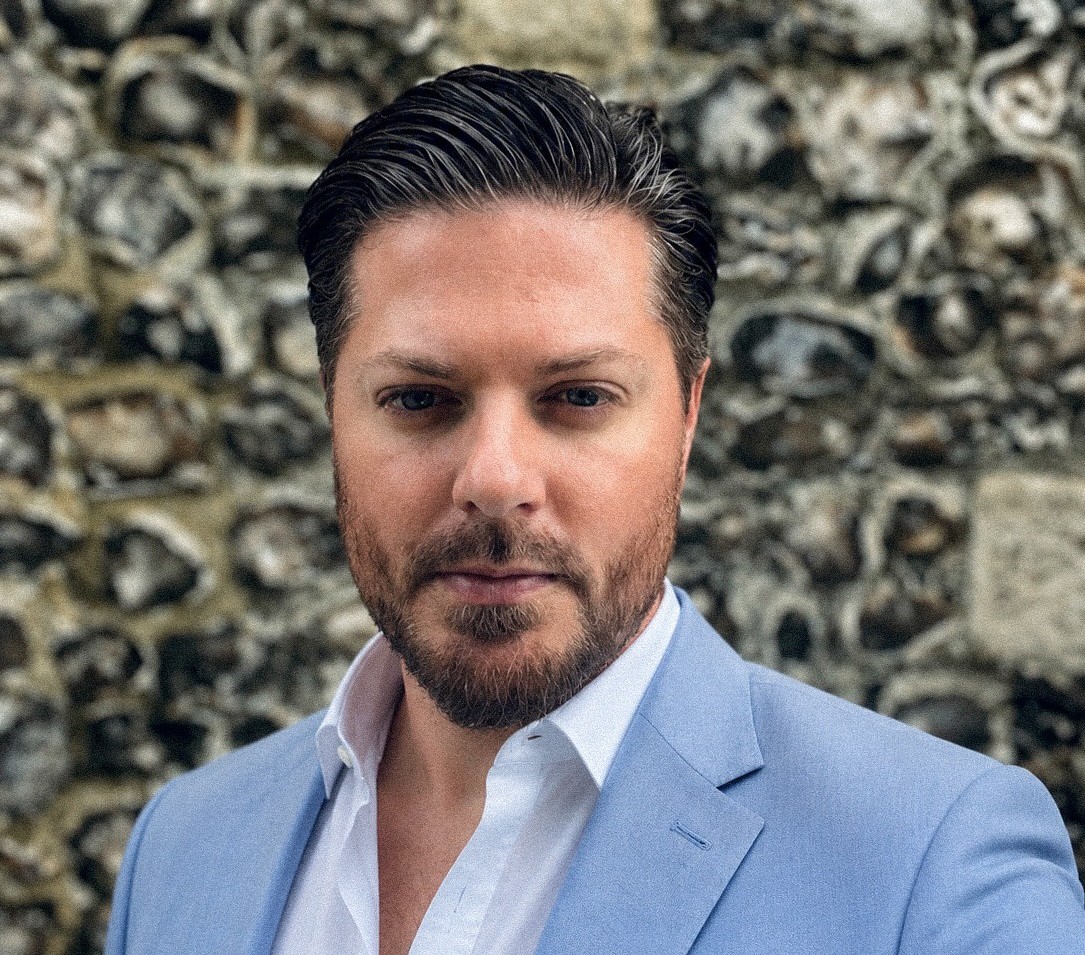 A  close up of Leon Mitchell with head and shoulder. He wears a light blue suit jacket and white shirt