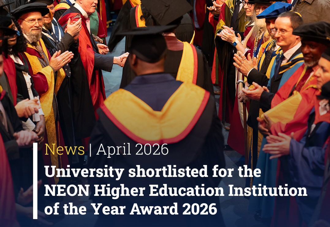 A photo of graduation day with students dressed in University of Wolverhampton gowns and caps. They are being applauded as they walk down a gangway.