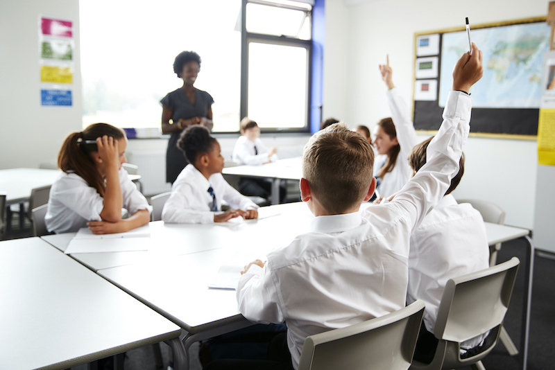 Header image of high school students wearing matching uniforms raising their hands