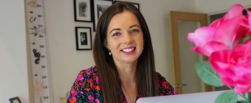 Ruth Lue-Quee smiling at camera sitting at desk
