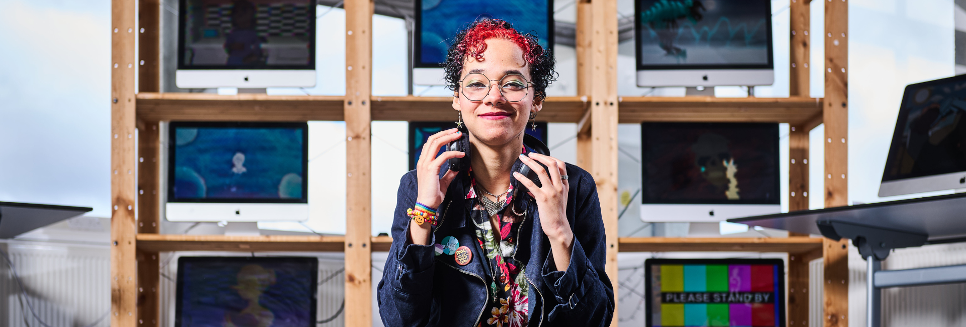 A student with headphones on in front of screens