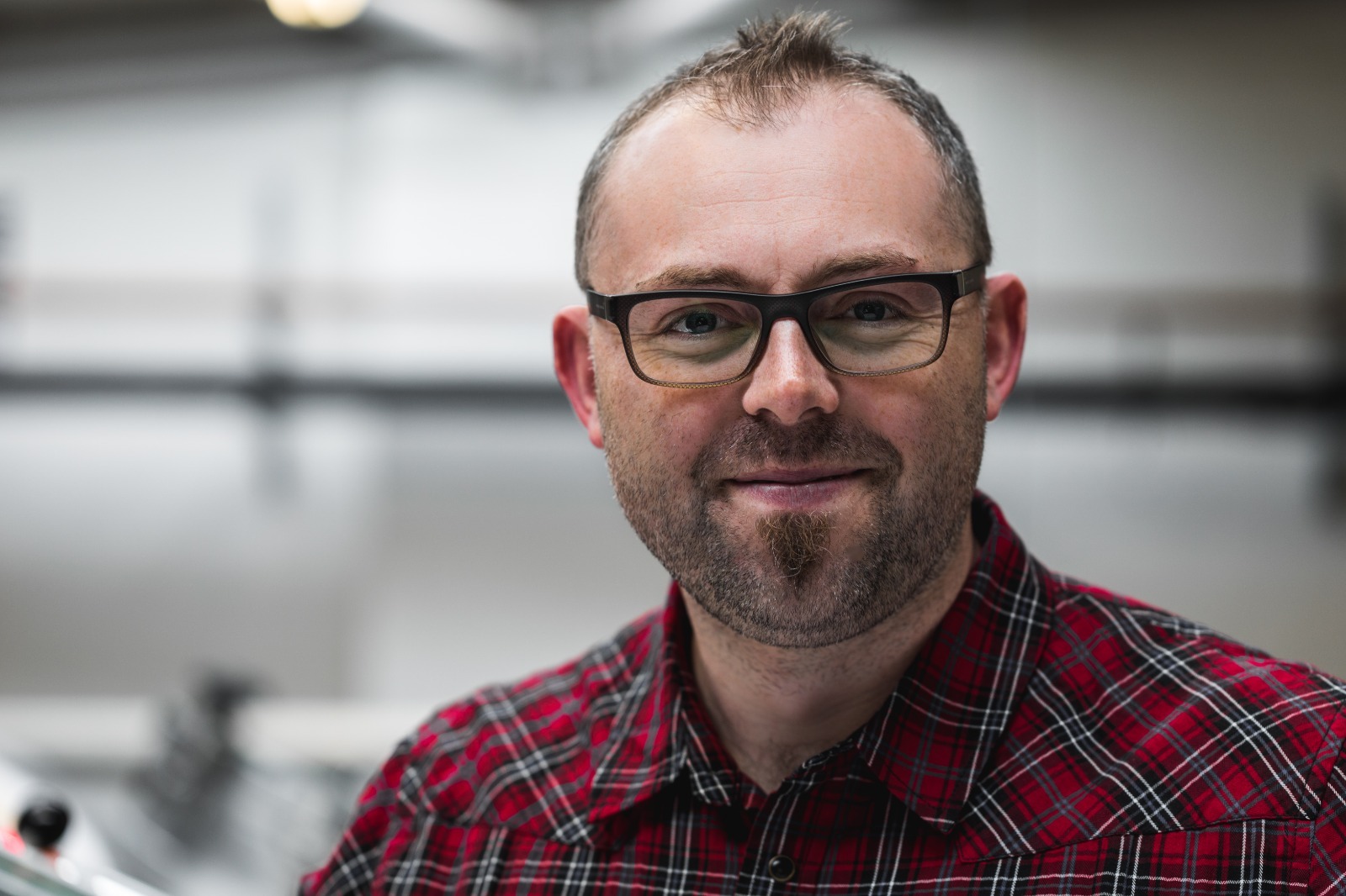 Headshot photograph of Jim Shirley wearing a red plaid shirt.