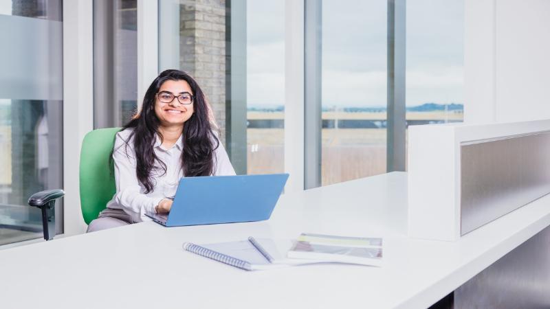 A student smiling at a laptop
