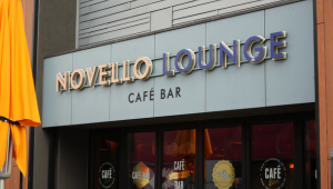 Sign for the Novello Lounge Cafe Bar, signage listing its name above glass double doors