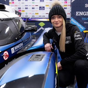 UWR race team student kneeling next to the UWR racecar