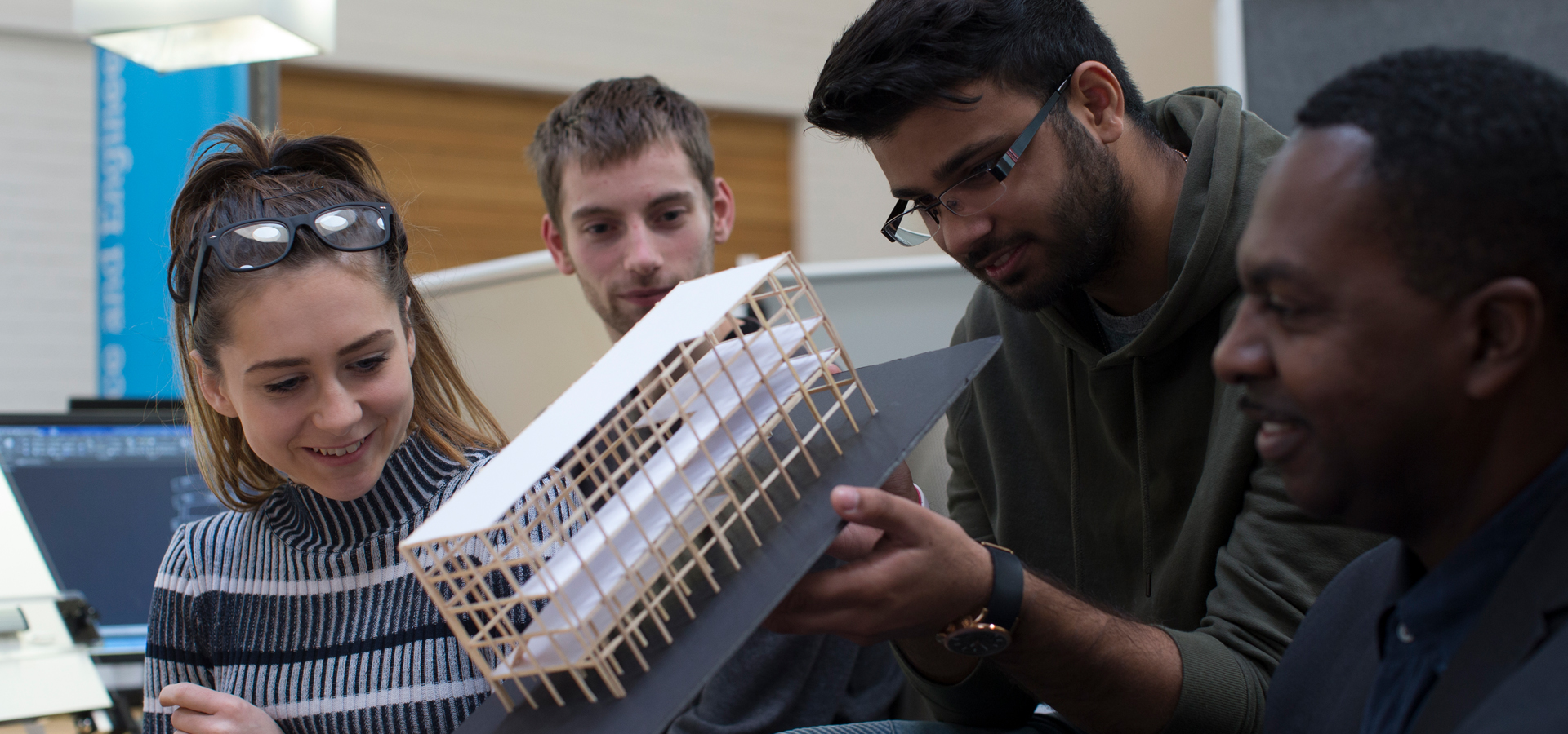 Architecture students in a classroom holding a model building