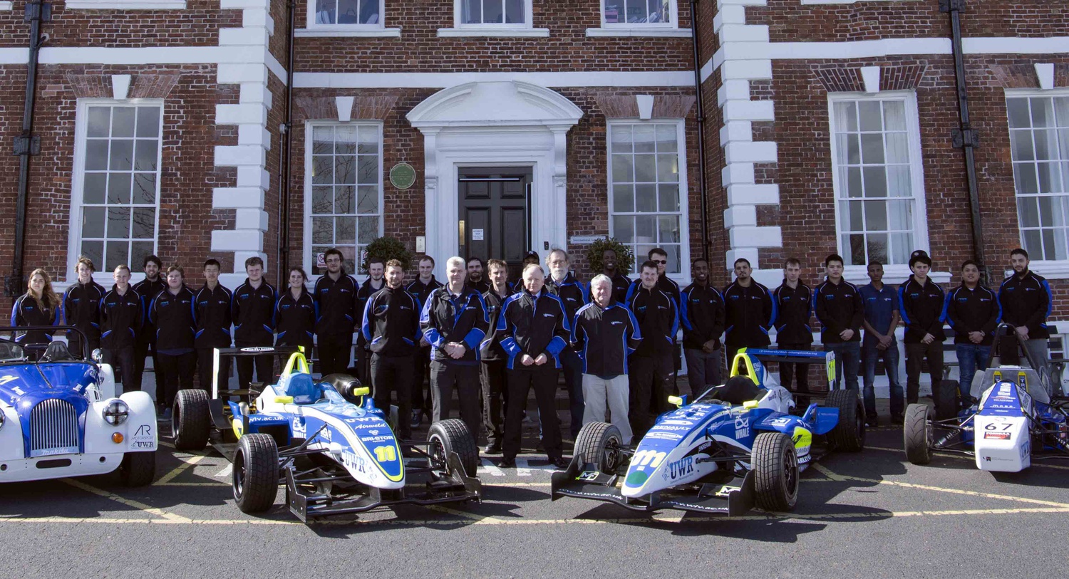 Row of Students standing behind two UWRacing cars