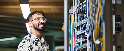 student standing with laptop looking at a server rack