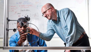 Staff member showing a student a mechanism with weights.