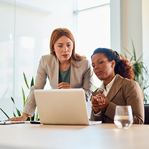 two colleagues looking over a laptop and talking