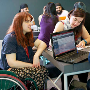 image of group of people suitting around laptop one in a wheelchair
