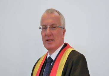 Photograph of Michael Elliott wearing a suit and academic robes.