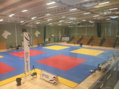 British Judo Association mats prepared in the University sports hall, overseen by rows of seats