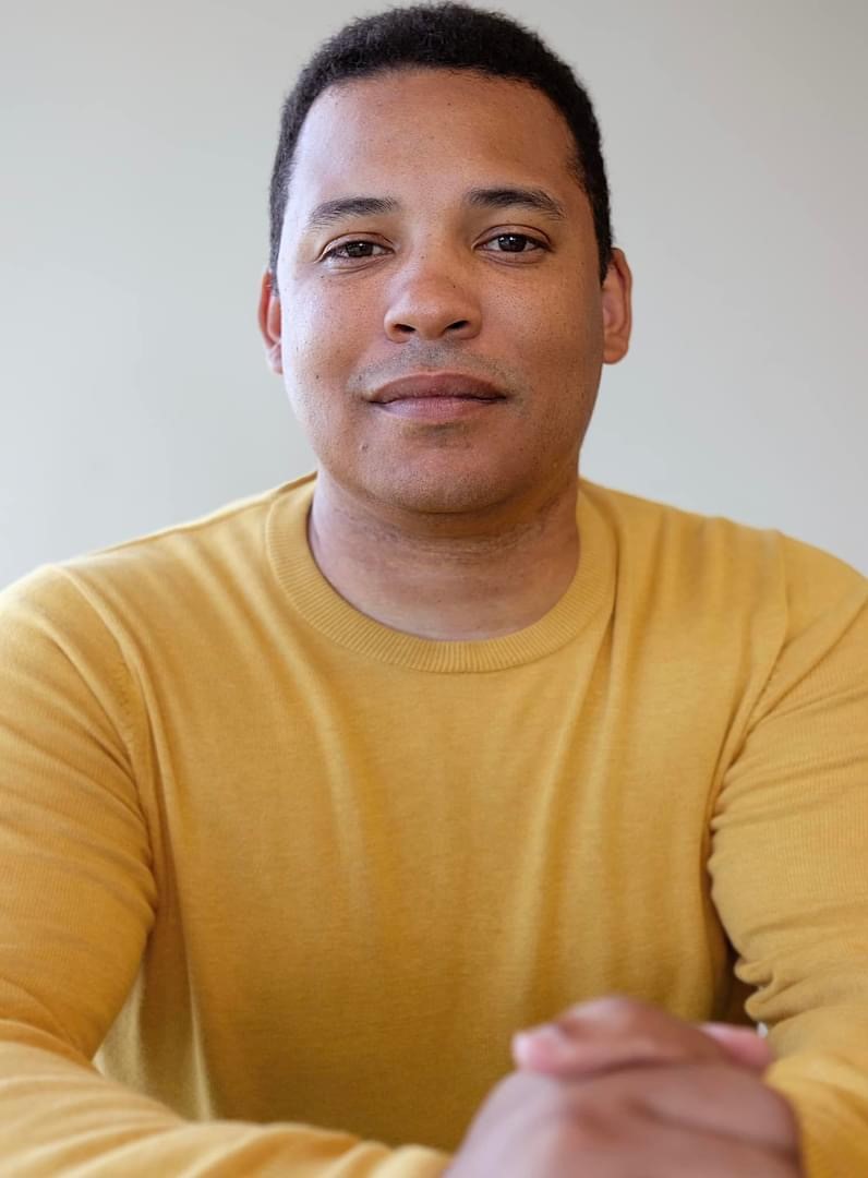 Photograph of Lee Wallis wearing a yellow shirt.