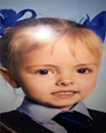 A photograph of Clare as a child, wearing her school uniform and blue ribbons in her hair.